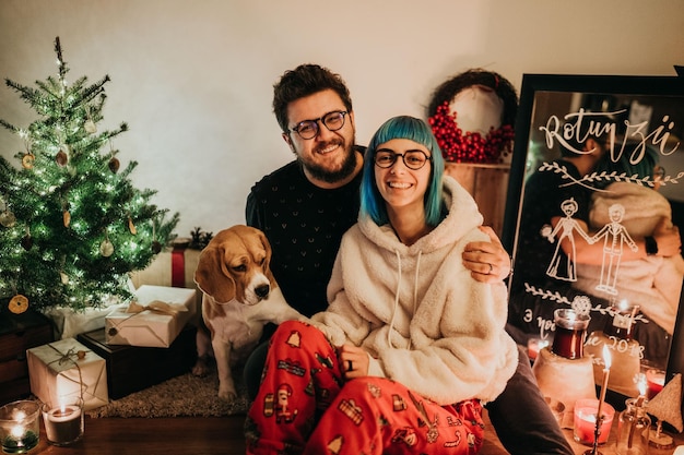 クリスマスの間に家で犬を飼っている笑顔のカップルの肖像画