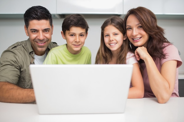 Портрет улыбающейся пары с детьми, используя ноутбук