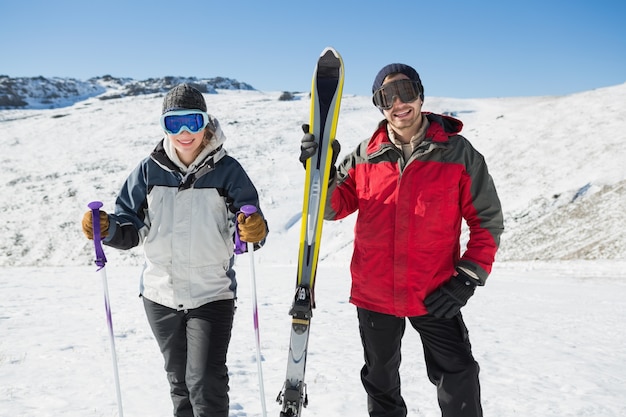 Portrait of a smiling couple with ski equipment on snow