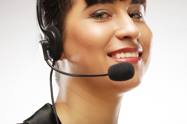 Portrait of smiling customer support female phone worker over w