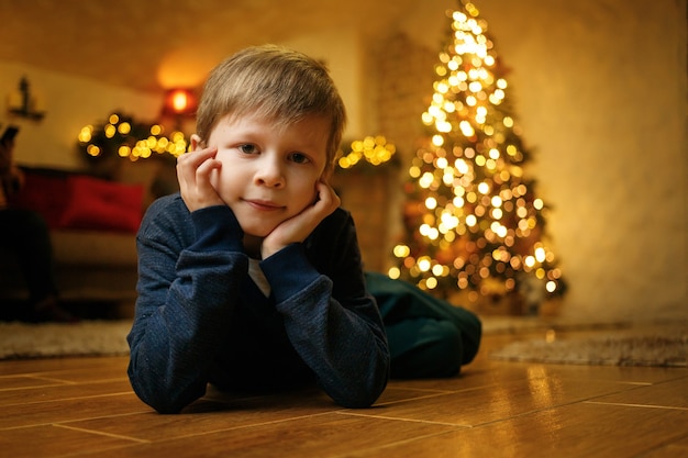 Portrait of a smiling cute boy 5-7 years old against the background of a Christmas tree