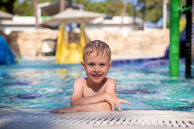 Portrait of smiling cute boy in the pool at the aquapark Concept summer vacation rest fun