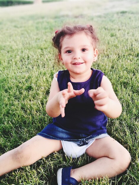 Photo portrait of smiling cute girl sitting on grassy field