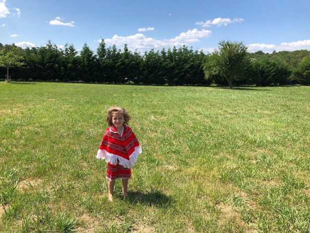 portrait of smiling cute girl standing on grassy field