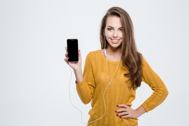 Portrait of a smiling cute woman showing blank smartphone screen isolated on a white background