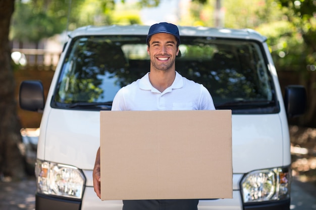 Photo portrait of smiling delivery person holding cardboard box