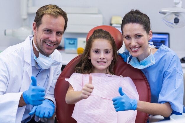 Портрет улыбающегося стоматолога и молодого пациента показывает палец вверх