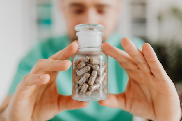 Portrait of a smiling doctor holding up a bottle with tablets or pills for treatment isolated on whi