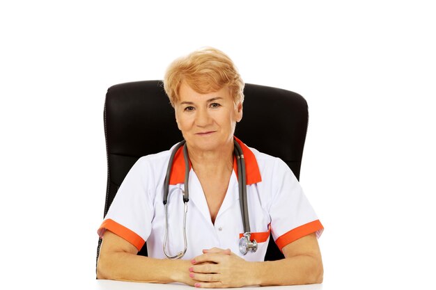 Photo portrait of smiling doctor sitting on chair against white background