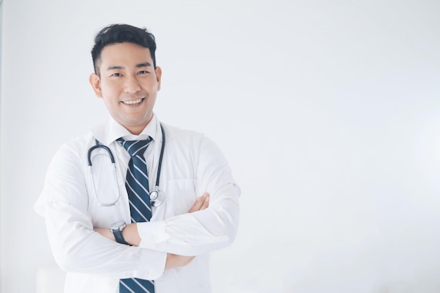 Photo portrait of smiling doctor with arms crossed against wall in hospital