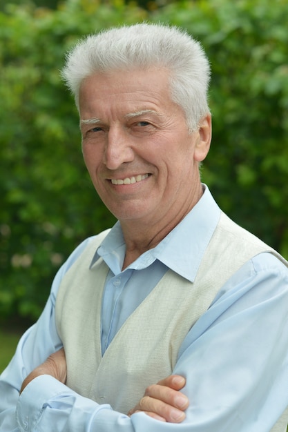 Photo portrait of smiling elderly man on green summer background