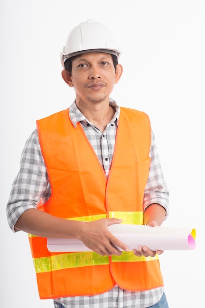 Portrait of smiling engineer holding blueprints while standing against white background