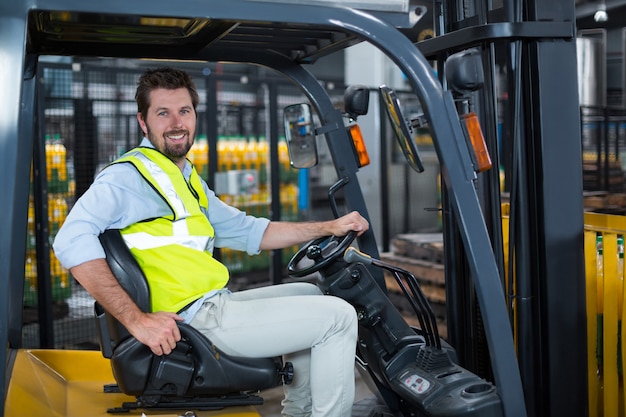 Photo portrait of smiling factory worker driving forklift