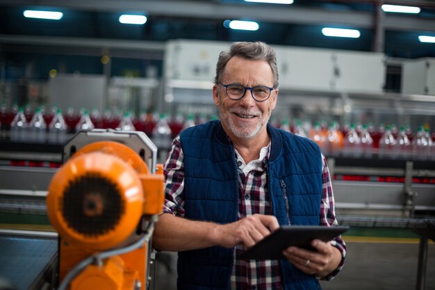 Portrait of smiling factory worker standing with a digital tablet in the factory