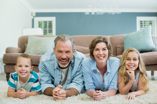 Foto ritratto di famiglia sorridente che si trovano insieme sul tappeto nel soggiorno