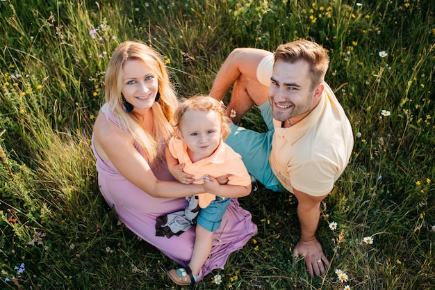 Photo portrait of smiling family sitting on field at park