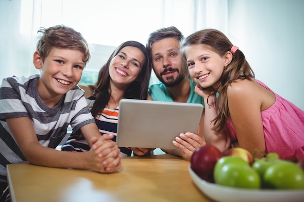 Portrait of smiling family using digital tablet while sitting at table