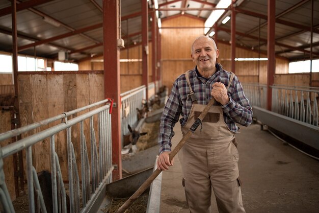 Portrait of smiling farmer or cattleman standing in farmhouse and feeding animals