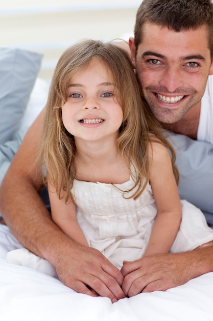 Portrait of smiling father and daughter in bed