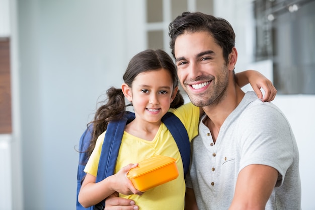 Portrait of smiling father and daughter with lunch box