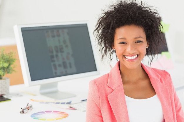 Portrait of a smiling female artist at desk with computer