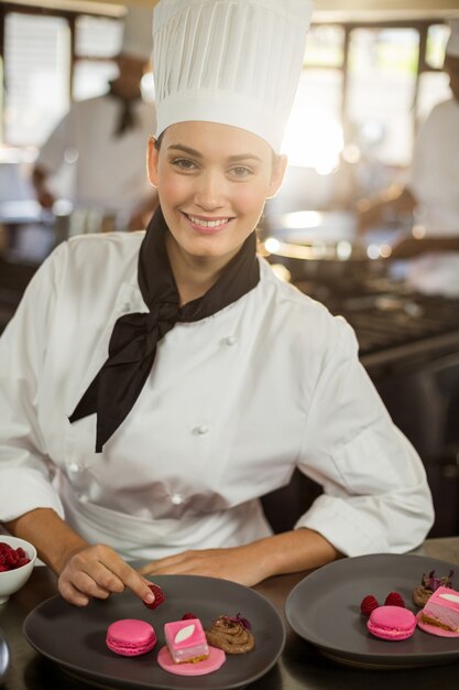 Photo portrait of smiling female chef finishing dessert plates