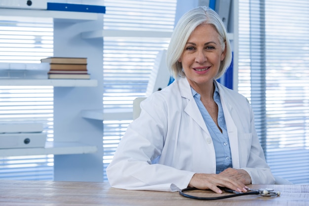 Портрет улыбающегося женщина-врач сидел на столе