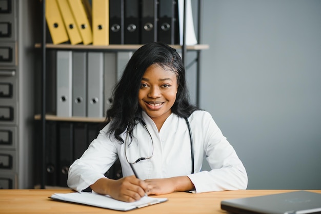 Портрет улыбающейся женщины-врача в белом халате со стетоскопом в офисе больницы