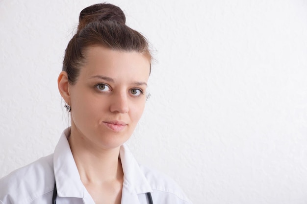 Portrait of a smiling female doctor in a white uniform on a white background