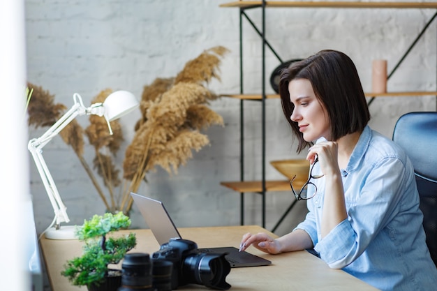 Portrait of smiling female freelancer using laptop.