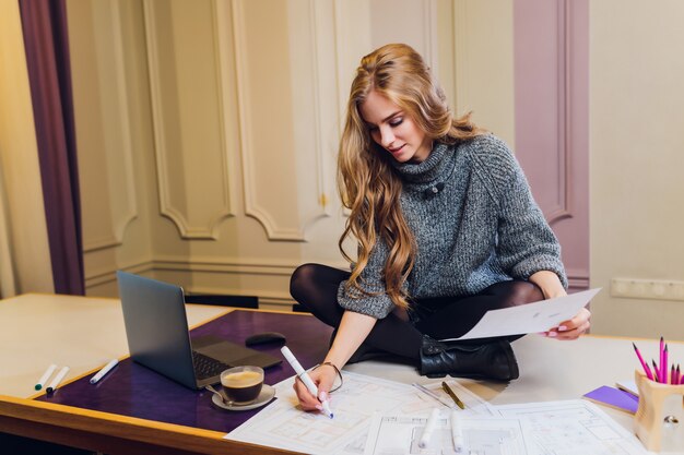 Portrait of smiling female interior designer sitting at office desk.