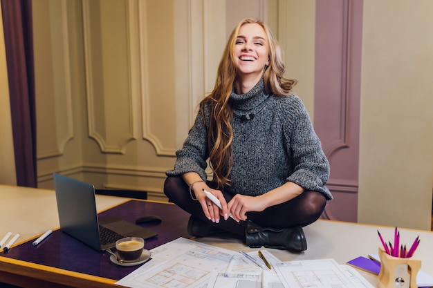 Portrait of smiling female interior designer sitting at office desk.