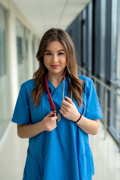 Portrait of smiling female medical worker in blue uniform with stethoscope at clinic.