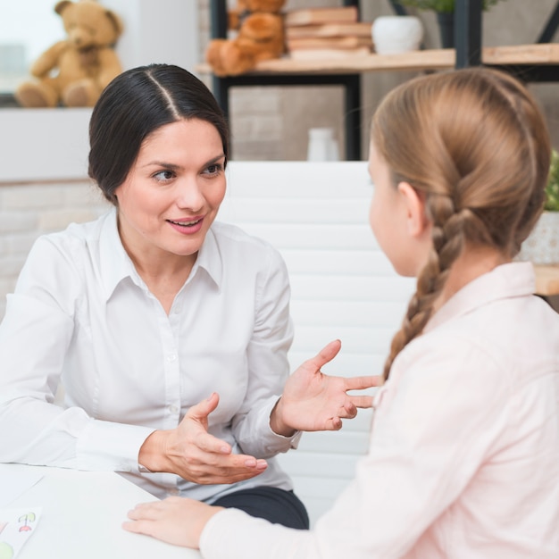 Photo portrait of a smiling female psychologist talking with girl in the office