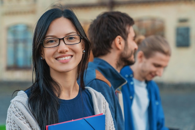 Portrait of smiling female student on the background with his cheerful classmates