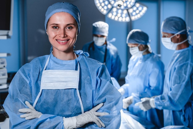 Portrait of smiling female surgeon with operation in\
background