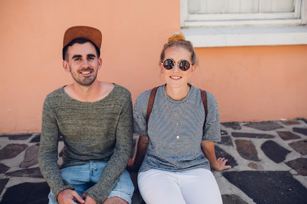 Photo portrait of smiling friends sitting against wall