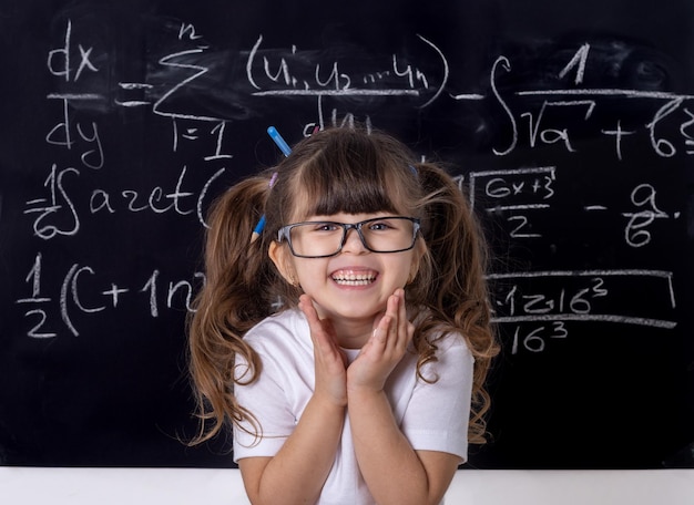 Photo portrait of smiling girl against blackboard in classroom