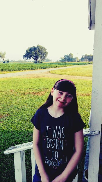 Photo portrait of smiling girl by railing at park