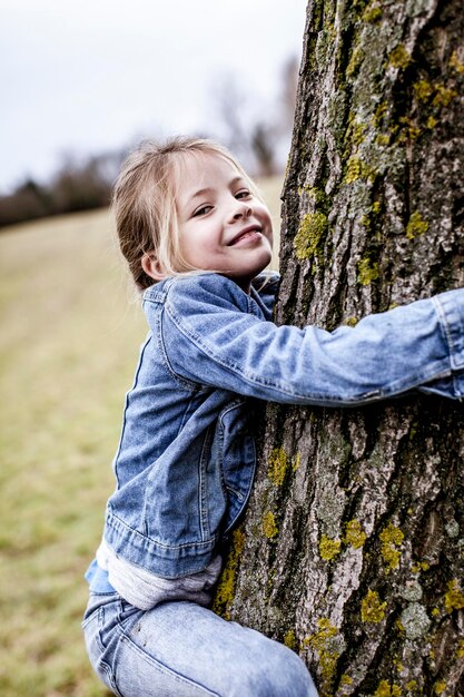 Portrait of smiling girl climbing tree on field