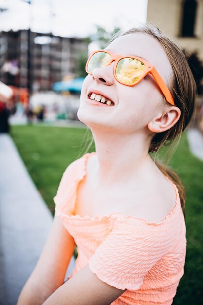 portrait of a smiling girl in funny orange glasses on the street