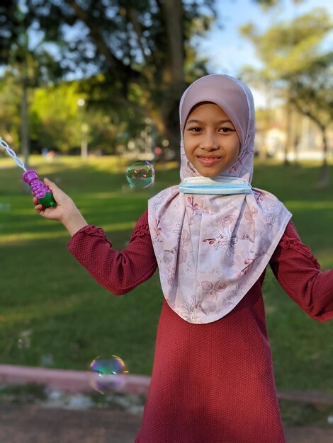 Photo portrait of a smiling girl holding bubbles