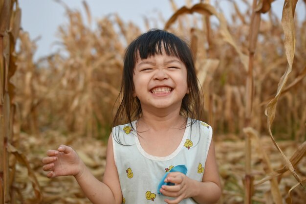 Portrait of smiling girl holding camera on field