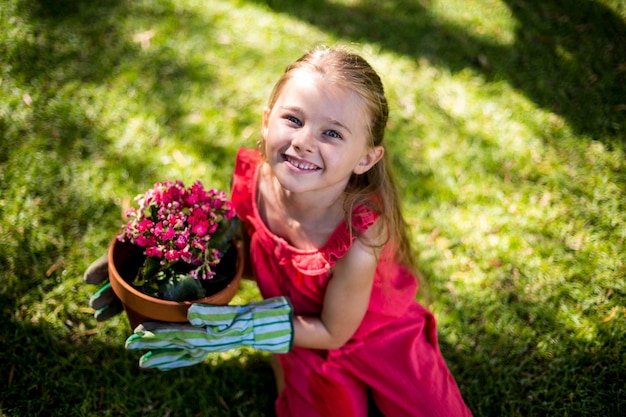 Portrait of smiling girl holding flower pot in yard