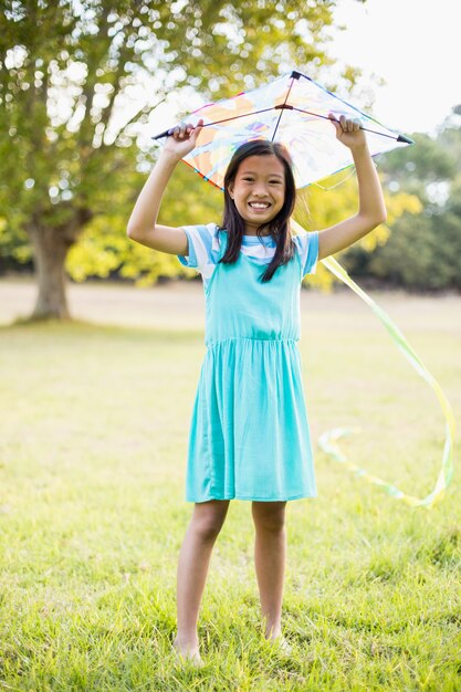 Portrait of smiling girl holding kite in park