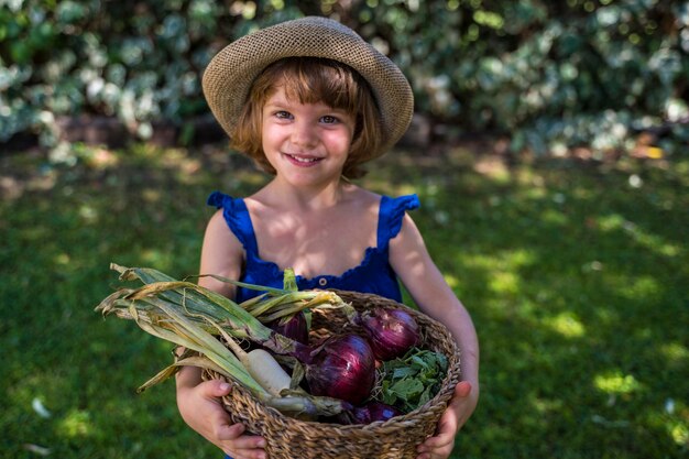 Portrait of smiling girl holding vegetables in basket