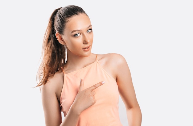 Portrait of a smiling girl pointing finger to the side at on a white isolated background Positive woman points to an idea a place for advertising