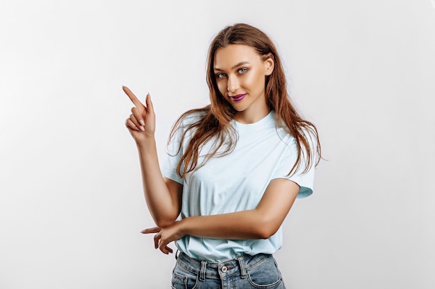 Portrait of a smiling girl pointing finger to the side at on a white isolated background