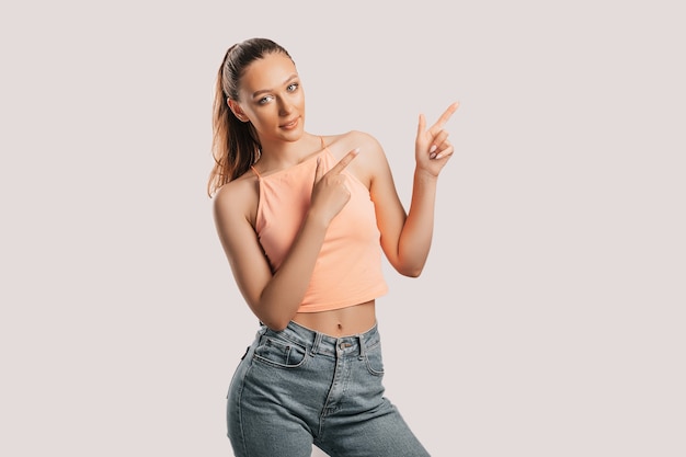 Portrait of a smiling girl pointing finger to the side at on a white isolated surface