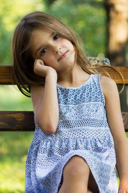 Photo portrait of smiling girl sitting on bench at park